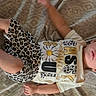 Maelyn is registered to the contest to win money with this photo: baby, child, infant, lying_down, bed, bedspread, leopard_print, outfit, shoes, hood, clothing, fashion, portrait, face, eyes, smiling, indoors, patterned, daisy, photograph