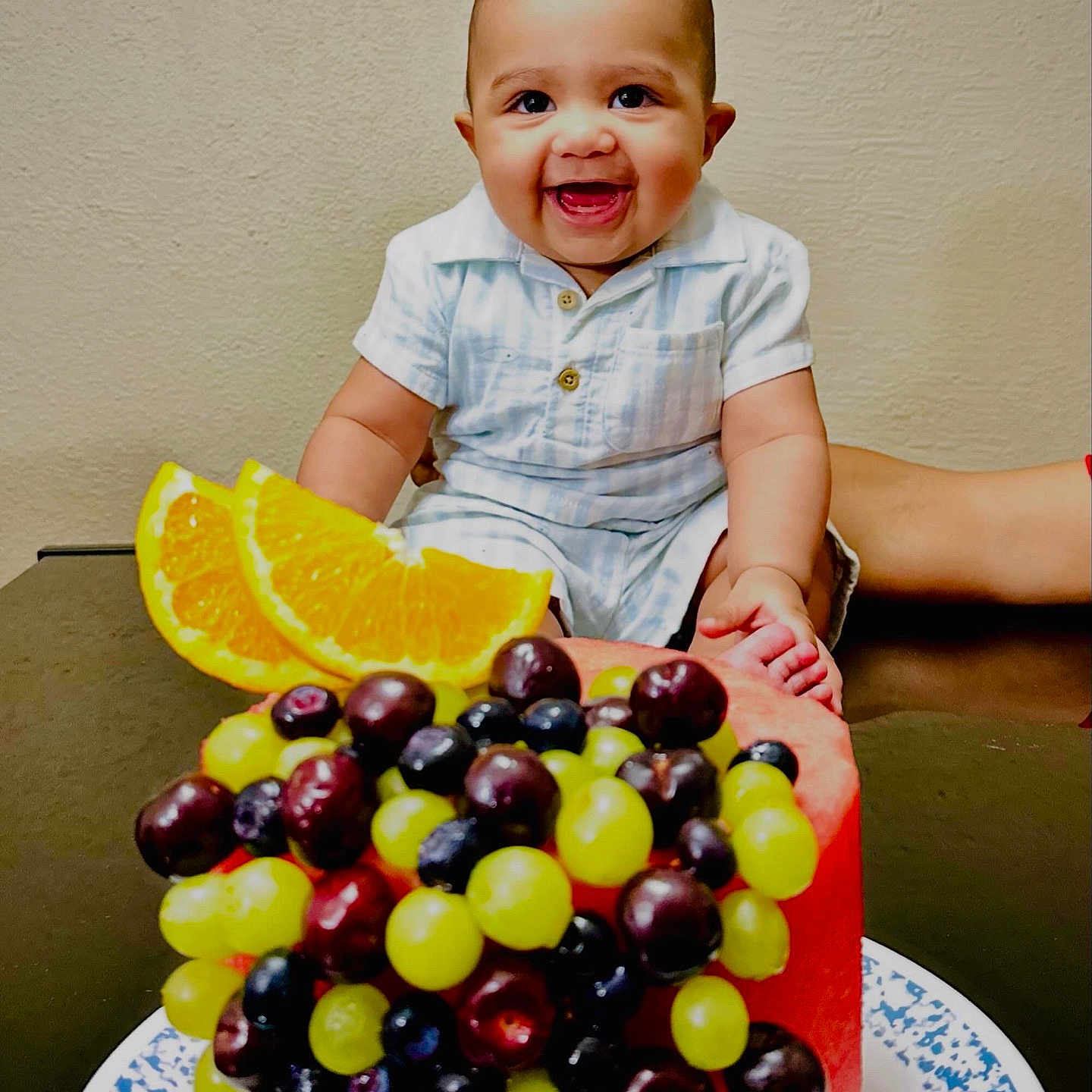 Nile is registered to the contest to win money with this photo: baby, blueberries, child, clothing, colorful, cute, food, fruit, grapes, happy, healthy, indoor, infant, orange_slices, person, plate, portrait, smile, table, watermelon