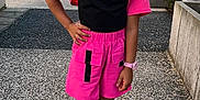 Sarah a rejoint le concours — aidez-le/la à gagner de superbes lots ! child, outdoor, sunglasses, pink_clothing, shorts, sandals, watch, urban, sidewalk, building, confident, person, fashion, summer, standing, hand_on_hip, young, casual, accessory, daylight