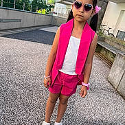 Sarah participe au concours pour gagner de l'argent avec cette photo : child, girl, outdoor, pink_clothing, shorts, vest, sunglasses, heart_shaped, hair_accessory, bracelet, watch, sandals, standing, urban, concrete, daylight, fashion, serious_expression, person, summer