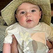 Roman is registered to the contest to win money with this photo: baby, child, hat, straw_hat, elephant, tshirt, hand, person, indoors, face, cute, young, smiling, looking, holding, apparel, clothing, infant, portrait, closeup