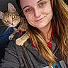 woman, cat, pet, selfie, smile, shoulder, tabby_cat, collar, indoor, long_hair, casual_clothing, hoodie, portrait, young_adult, human, animal, cute, friendship, happy, closeup