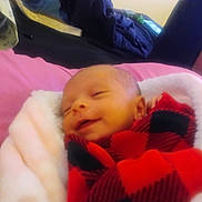 Jordyn joined the competition — help win amazing prizes! baby, bedroom, blanket, checkered, child, comfort, cozy, cushion, face, head, indoor, infant, peaceful, person, red_and_black, resting, sleeping, smiling, soft, wrapped