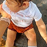 Khealani is registered to the contest to win money with this photo: baby, casual_clothing, child, curly_hair, footwear, hand, holding_hand, looking_away, orange_shorts, outdoor, person, skin, sneakers, stone_surface, sunlight, toddler, wet_hair, white_shirt, white_socks, young_child