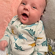 Aksel joined the competition — help win amazing prizes! baby, infant, smiling, dinosaur_print, onesie, cute, chubby_cheeks, happy, portrait, indoor, child, young, person, face, clothing, closeup, cozy, pink_background, grey_background, joyful