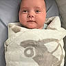 Aksel is registered to the contest to win money with this photo: baby, blanket, wrapped, infant, face, soft, cute, cozy, expression, gaze, newborn, comfort, smile, animal_pattern, indoor, portrait, child, resting, warm, peaceful