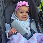 Araceli is registered to the contest to win money with this photo: baby, child, smiling, headband, flower, blanket, stroller, outdoor, hoodie, happy, cute, infant, person, seatbelt, warm_clothing, pink, white, soft, portrait, cozy