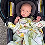 baby, car_seat, blanket, outdoor, infant, child, tongue, expression, playful, safety_warning, fabric, seatbelt, person, cute, bundle, colorful, soft, head, face, car