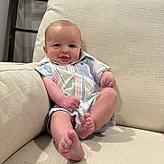 Rowdy is registered to the contest to win money with this photo: baby, infant, smiling, couch, indoor, clothing, striped_shirt, barefoot, comfortable, cheerful, cute, face, skin, head, legs, feet, furniture, relaxing, young_child, portrait