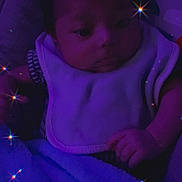 Jose Antonio joined the competition — help win amazing prizes! baby, infant, blanket, bib, purple_light, sparkles, face, hand, sleeping_area, child, cute, soft_texture, portrait, dark, indoors, cozy, young, resting, peaceful, person