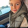 child, boy, car, seat, window, vest, clothing, portrait, smile, face, hand, casual, jeans, natural_light, indoor, young, cute, expression, sitting, affection