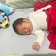 Basthian joined the competition — help win amazing prizes! baby, sleeping, infant, bed, blanket, plush_toy, stuffed_animal, blue_toy, red_blanket, white_clothing, portrait, indoors, bedroom, peaceful, resting, face, closed_eyes, hand, bedding, cozy