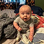 baby, infant, child, bed, blanket, pillow, curtain, onesie, sock, surprised_expression, sitting, face, eyes, mouth_open, soft_texture, plush, indoor, portrait, cozy, bedding
