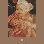 Ariella is registered to the contest to win money with this photo: baby, bodypart, bonnet, cap, clothing, costume, dress, face, fashion, finger, formalwear, gown, hand, hat, head, newborn, person, photography, portrait, sitting