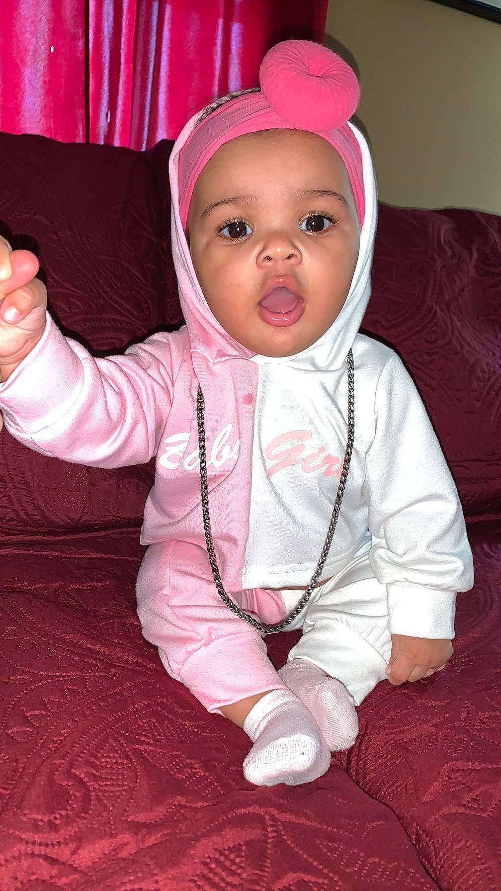 Ayana is registered to the contest to win money with this photo: baby, baby_toddler_clothing, cheek, comfort, eye, eyebrow, face, finger, gesture, happy, head, headwear, human_body, jacket, lip, mouth, nose, person, pink, skin
