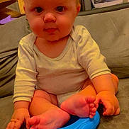 Ethan participe au concours pour gagner de l'argent avec cette photo : baby, child, infant, couch, blue_toy, feet, hands, onesie, cross_legged, indoor, high_chair, wooden_stairs, curly_hair, expression, face, person, seated, furniture, cute, skin