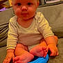 baby, child, infant, couch, blue_toy, feet, hands, onesie, cross_legged, indoor, high_chair, wooden_stairs, curly_hair, expression, face, person, seated, furniture, cute, skin