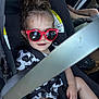 Chevelle is registered to the contest to win money with this photo: toddler, child, car_seat, sunglasses, red_glasses, seatbelt, car_interior, black_clothing, white_clothing, patterned_shirt, hair_tied_up, legs, hand, safety, vehicle, cute, portrait, baby, child_safety, casual