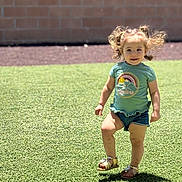 Chevelle joined the competition — help win amazing prizes! toddler, child, grass, outdoor, sunny, happy, curly_hair, shorts, sandals, brick_wall, playful, green, casual_clothing, daylight, smiling, young_child, active, person, summer, nature