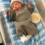 Ronan is registered to the contest to win money with this photo: newborn, baby, infant, blanket, bassinet, beanie, knit_sweater, name_on_clothing, wooden_name_tag, crocheted_blanket, smile, sleeping, hospital_id_band, sock, cozy, soft_texture, portrait, cute, hand, nursery