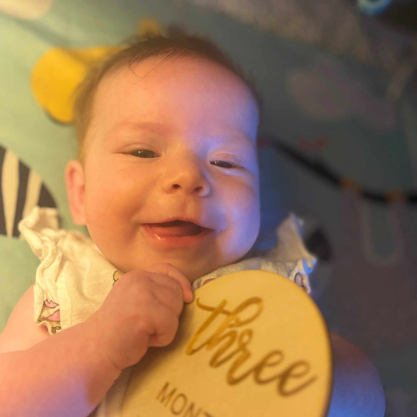 Aerilyn is registered to the contest to win money with this photo: baby, background, child, closeup, clothing, cute, face, hand, happy, indoor, infant, person, portrait, skin, smile, soft_light, text, three_months, wooden_plaque, young