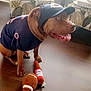 dog, pet, indoor, plush_toy, football_toy, beer_bottle_toy, hat, jersey, floor, furniture, chair, table, window, light, brown_dog, happy, sitting, home, decor, cozy