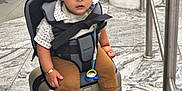 Ismael joined the competition — help win amazing prizes! airport, bracelet, car_seat, child, curly_hair, floor, hand, luggage, metal_rail, pacifier, pants, person, seatbelt, shirt, shoes, suitcase, toddler, travel, waiting_area, wall
