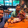 Lakshmi joined the competition — help win amazing prizes! baby, cafe, casual, chair, child, coffee, cup, family, happy, indoor, man, parent, people, portrait, relaxed, seated, smile, table, waving, woman
