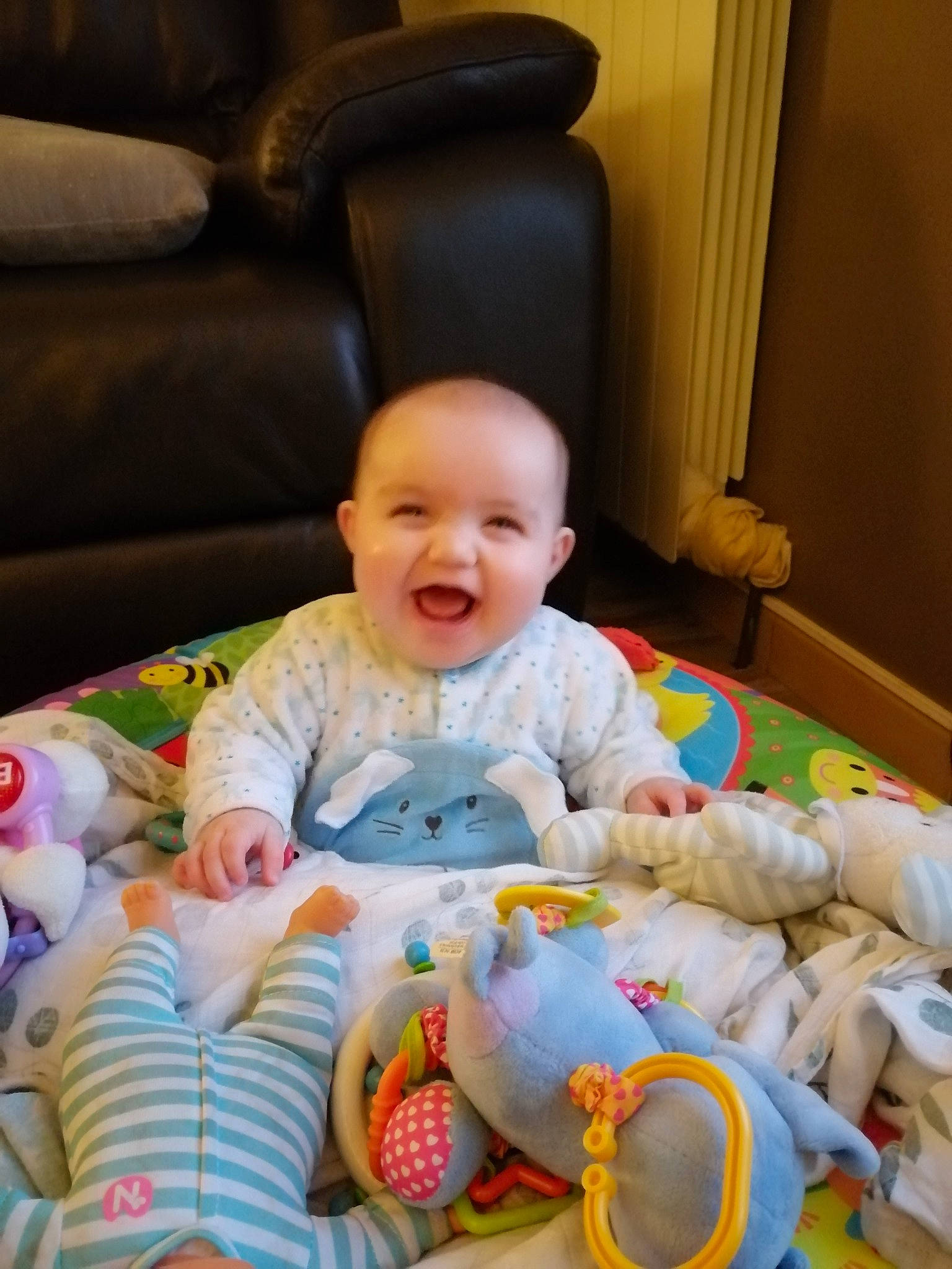 Mathilde participe au concours pour gagner de l'argent avec cette photo : baby, baby_products, baby_toddler_clothing, cheek, child, comfort, flooring, fun, happy, linens, people, person, play, room, sitting, skin, smile, textile, toddler, toy