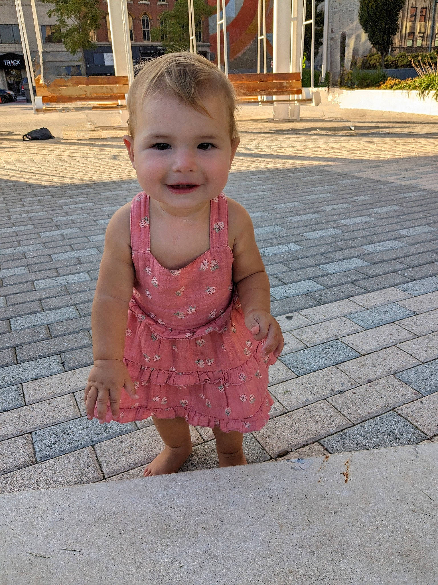 Isabel is registered to the contest to win money with this photo: asphalt, baby, baby_toddler_clothing, child, dress, flooring, fun, grass, happy, head, joy, leisure, magenta, person, pink, plant, road_surface, sidewalk, skin, smile