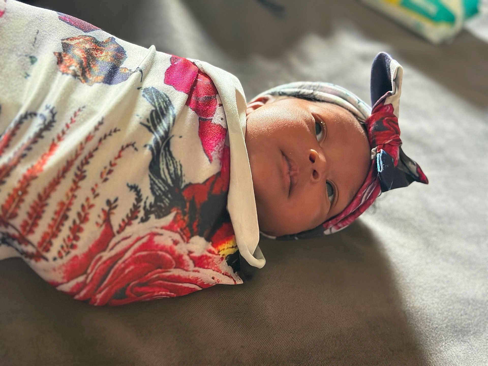 Autumn is registered to the contest to win money with this photo: baby, infant, swaddled, headband, floral_pattern, soft_lighting, portrait, closeup, face, newborn, lying_down, blanket, colorful, fabric, cute, peaceful, indoors, skin, expression, background_blur