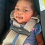 baby, child, car_seat, safety_straps, blue_shirt, pink_flowers, smiling, face, portrait, infant, seatbelt, cute, young_child, skin, head, eyes, expression, indoor, person, clothing