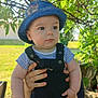 Louis participe au concours pour gagner de l'argent avec cette photo : baby, child, blue_hat, striped_shirt, overalls, outdoor, greenery, tree, leaves, sunlight, hand, face, curious, grass, summer, person, nature, daylight, cute, portrait
