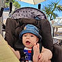 Louis participe au concours pour gagner de l'argent avec cette photo : baby, denim_hat, stroller, outdoor, cafe, umbrella, palm_tree, sunny, blue_sky, foot, hand, face, child, happy, summer, seat, table, chair, clothing, expression