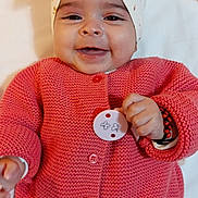 Sofiana participe au concours pour gagner de l'argent avec cette photo : baby, smiling, headband, pink_sweater, button, hand, infant, cute, lying_down, happy, face, skin, clothing, knitted, person, child, cozy, accessory, soft, portrait