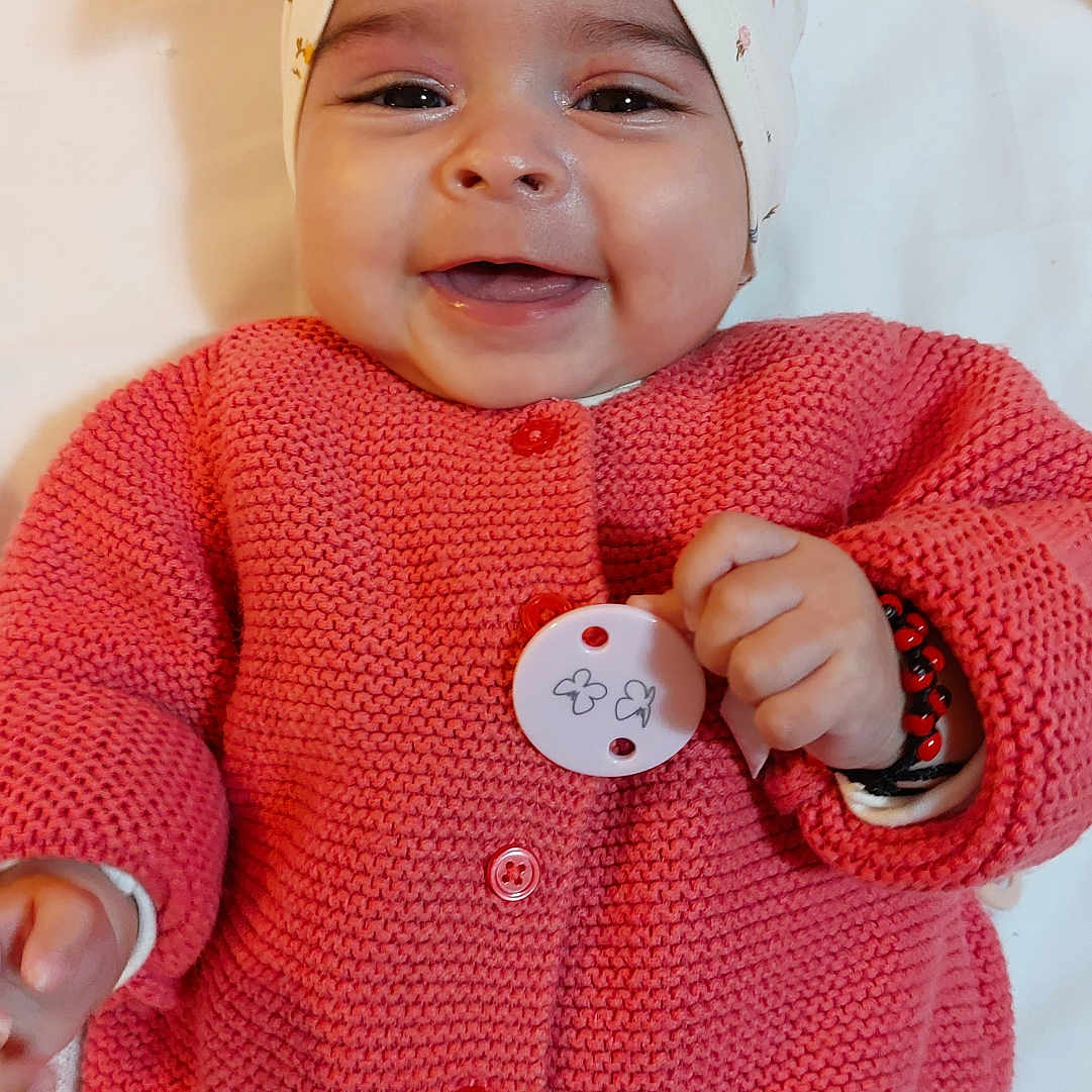 Sofiana participe au concours pour gagner de l'argent avec cette photo : accessory, baby, button, child, clothing, cozy, cute, face, hand, happy, headband, infant, knitted, lying_down, person, pink_sweater, portrait, skin, smiling, soft