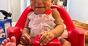 Jaxlynn joined the competition — help win amazing prizes! baby, child, curly_hair, cute, dimples, foot, furniture, hand, happy, home, indoors, infant, kitchen, light, person, pink_dress, red_baby_seat, seated, smile, table