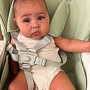Memory is registered to the contest to win money with this photo: baby, child, childhood, comfort, curly_hair, cute, expression, face, harness, high_chair, indoors, infant, looking, onesie, person, safety, seat, sitting, skin, young
