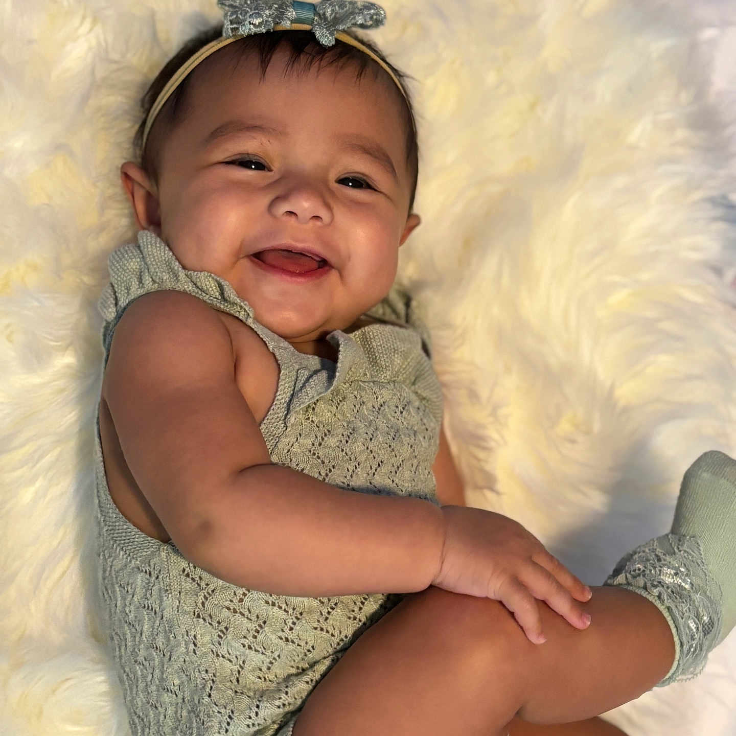 Alivia is registered to the contest to win money with this photo: baby, blanket, child, clothing, cozy, cute, face, hand, happy, headband, indoor, infant, leg, one_person, portrait, relaxing, skin, smiling, sock, soft_texture