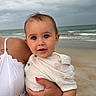 baby, beach, casual, child, closeup, cloudy_sky, cute, hand, holding, human, ocean, outdoor, person, portrait, sand, sky, toddler, water, waves, white_clothing
