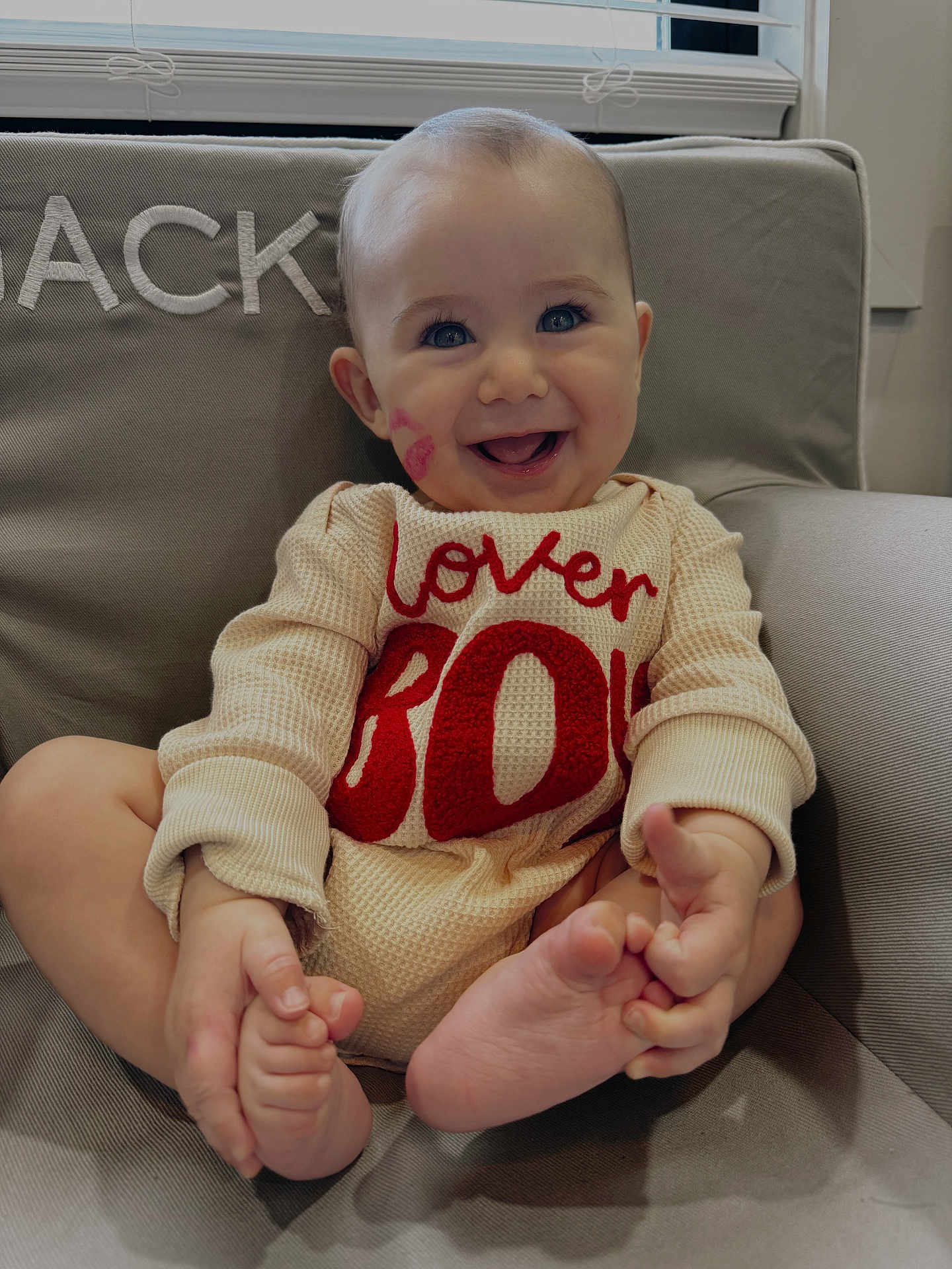 Wesley is registered to the contest to win money with this photo: baby, child, smile, happy, face, eyes, armchair, clothing, indoor, foot, hand, cute, infant, sitting, expression, cozy, window, lipstick_mark, red_text, portrait