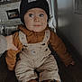 Wesley joined the competition — help win amazing prizes! baby, child, blue_eyes, beanie, overalls, brown_hoodie, indoor, wooden_surface, smiling, cute, person, footwear, hand, light_switch, cozy, expression, fashion, portrait, sitting, casual