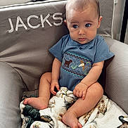 Wesley joined the competition — help win amazing prizes! baby, infant, child, blue_shirt, blanket, duck_pattern, chair, embroidery, name, curious, indoors, window, soft_texture, cute, seated, person, foot, hand, expression, cozy