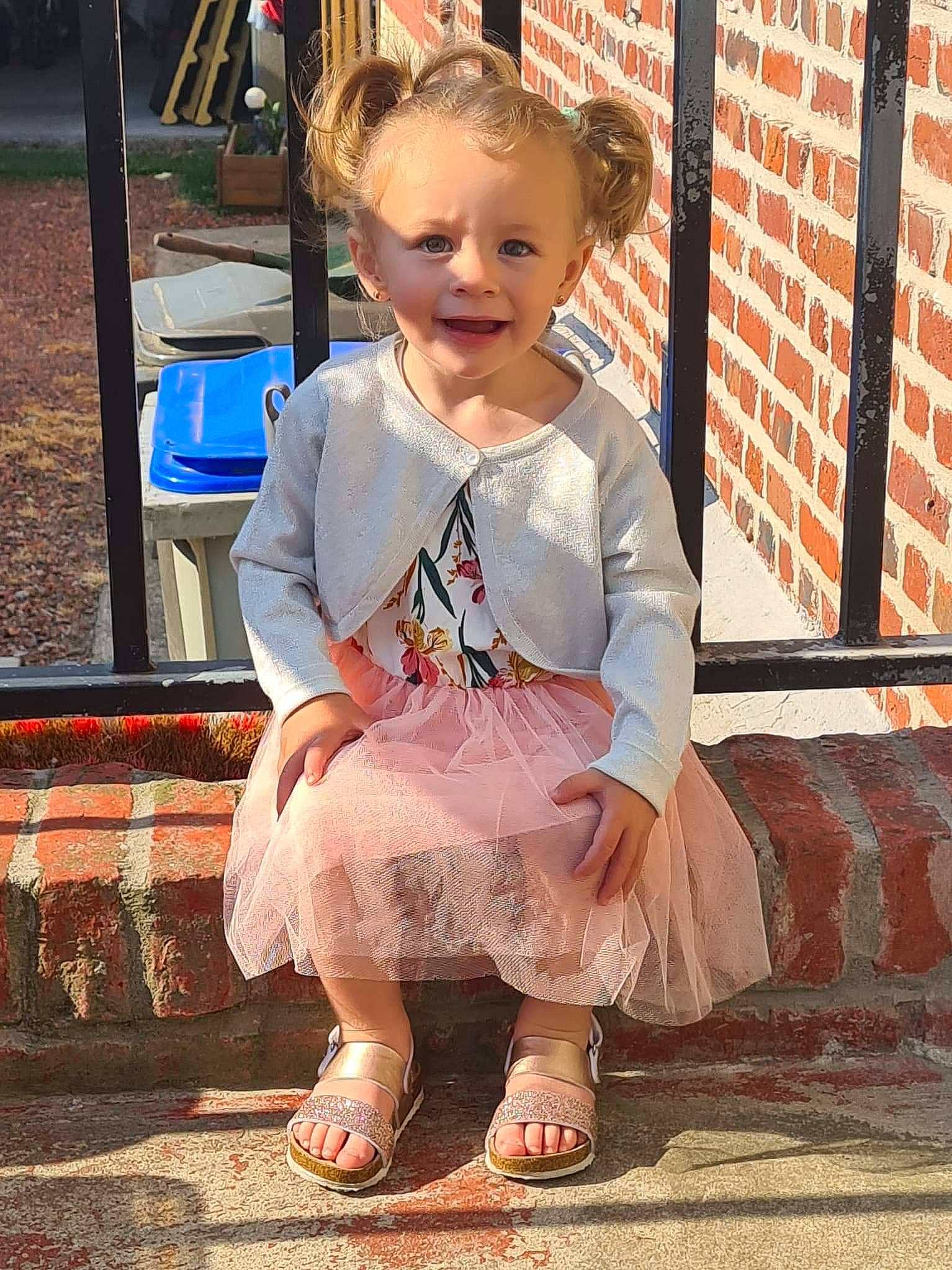 Zahyana a rejoint le concours — aidez-le/la à gagner de superbes lots ! baby, baby_toddler_clothing, brick, brickwork, child, dress, face, foot, fun, grass, hairstyle, happy, human_leg, leisure, person, pink, sandal, shoe, sitting, smile