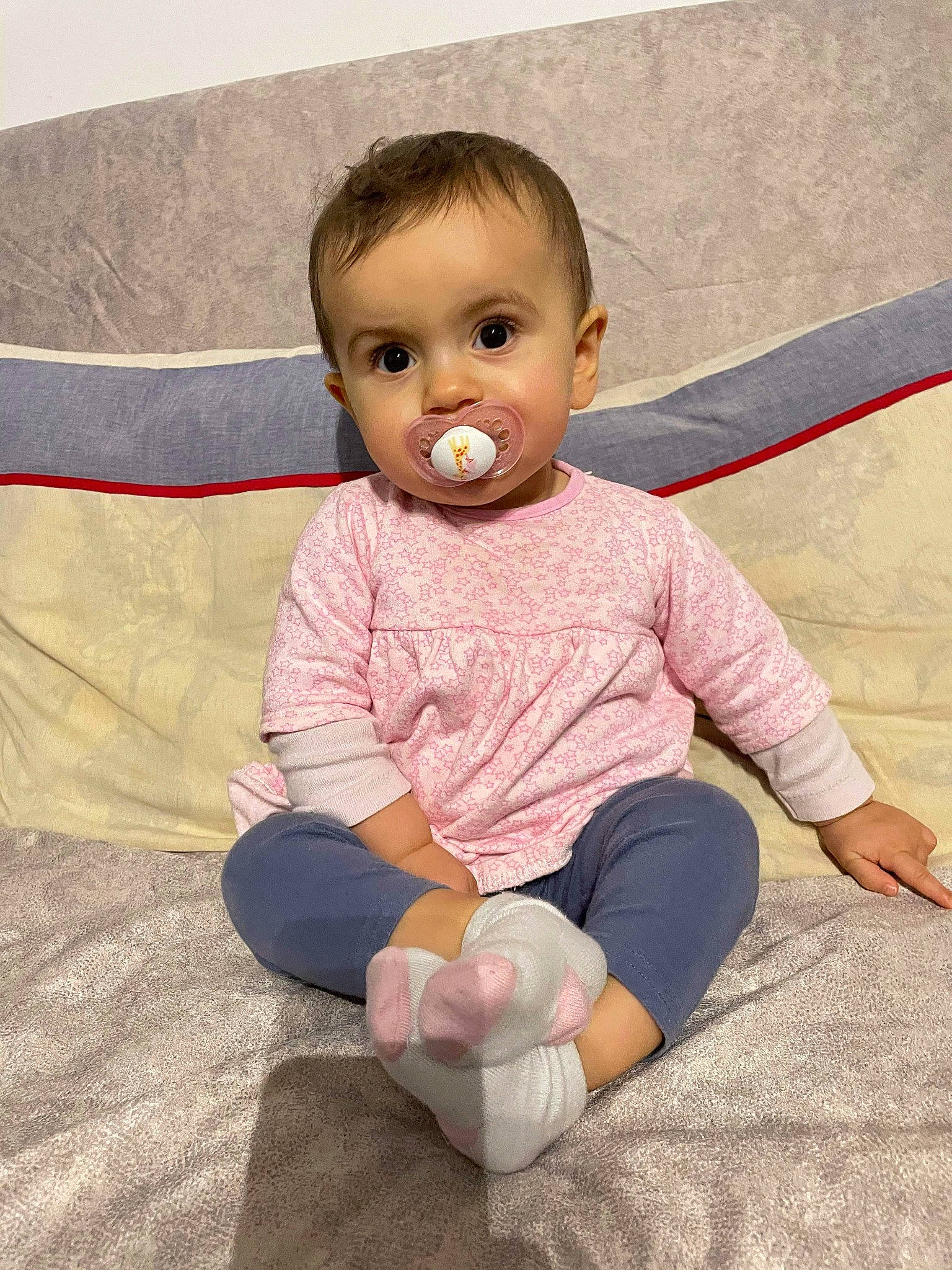 Houlya participe au concours pour gagner de l'argent avec cette photo : baby, baby_toddler_clothing, barefoot, cheek, comfort, eye, floor, flooring, foot, happy, human_body, human_leg, knee, person, pink, sitting, skin, sleeve, sock, t_shirt