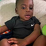 baby, beige, black_shirt, casual, child, closeup, couch, curly_hair, foot, furniture, hand, indoor, looking_away, nike_logo, person, relaxed, seated, skin, texture, toddler