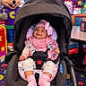 arcade, baby, baby_carrier, carpet, child, chuck_e_cheese, colorful, entertainment, happy, indoor, infant, mascot, pink_bow, pink_outfit, play_center, portrait, safety_harness, seated, smiling, stroller