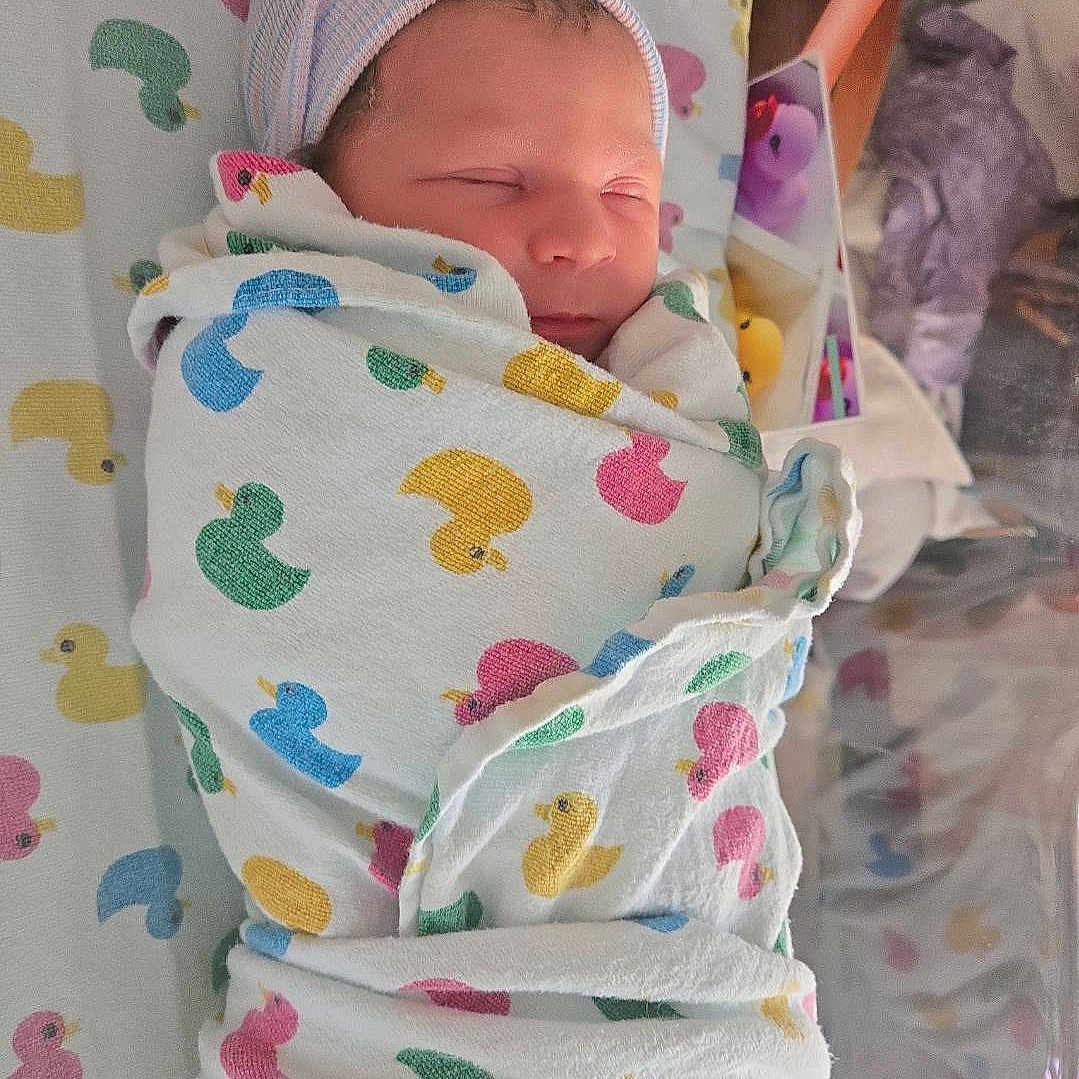 Brayleanna is registered to the contest to win money with this photo: baby, bed, blanket, child, colorful, cozy, crib, cute, duck_pattern, fabric, hat, indoor, infant, newborn, peaceful, resting, sleeping, soft_toys, striped_hat, swaddled