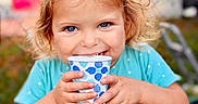 Harper joined the competition — help win amazing prizes! toddler, child, girl, blue_eyes, bow, turquoise_dress, polka_dots, paper_cup, smiling, happy, outdoor, portrait, curly_hair, cute, hands, face, person, daylight, background_blur, playful
