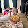 Harper joined the competition — help win amazing prizes! child, girl, indoor, curtains, carpet, wood_floor, pink_bow, yellow_cardigan, dress, table, chair, toy, playroom, daylight, smiling, seated, cute, floor, holding, pigtails